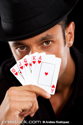 male magician covering his face with cards - i...